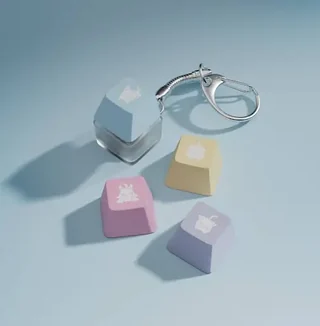 タレントのモチーフ絵が入った水色・黄色・ピンク・紫のキーキャップ4個（1個はキーホルダー付き）