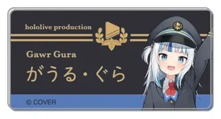 がうる・ぐらの名札バッジ Tokyo Station ver. の見本。黒い名札に「hololive production」「Gawr Gura」「がうる・ぐら」の文字と、駅員の帽子をかぶった絵柄があります。