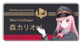 森カリオペの名札バッジ Tokyo Station ver. の見本。黒い名札に「hololive production」「Mori Calliope」「森カリオペ」の文字と、駅員の帽子をかぶった絵柄があります。